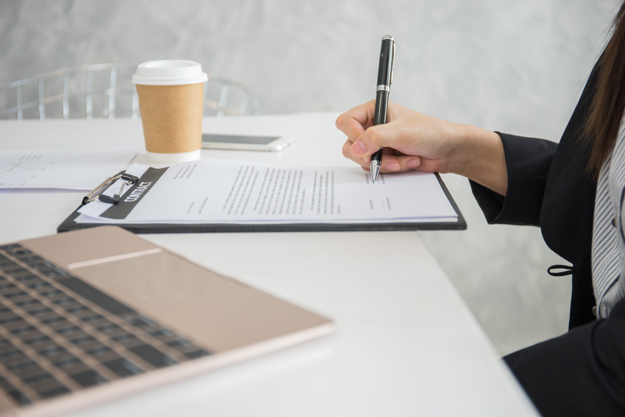 Close Up of business woman’s hand writing signature on contract