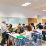 Diverse college students learning with professor in classroom
